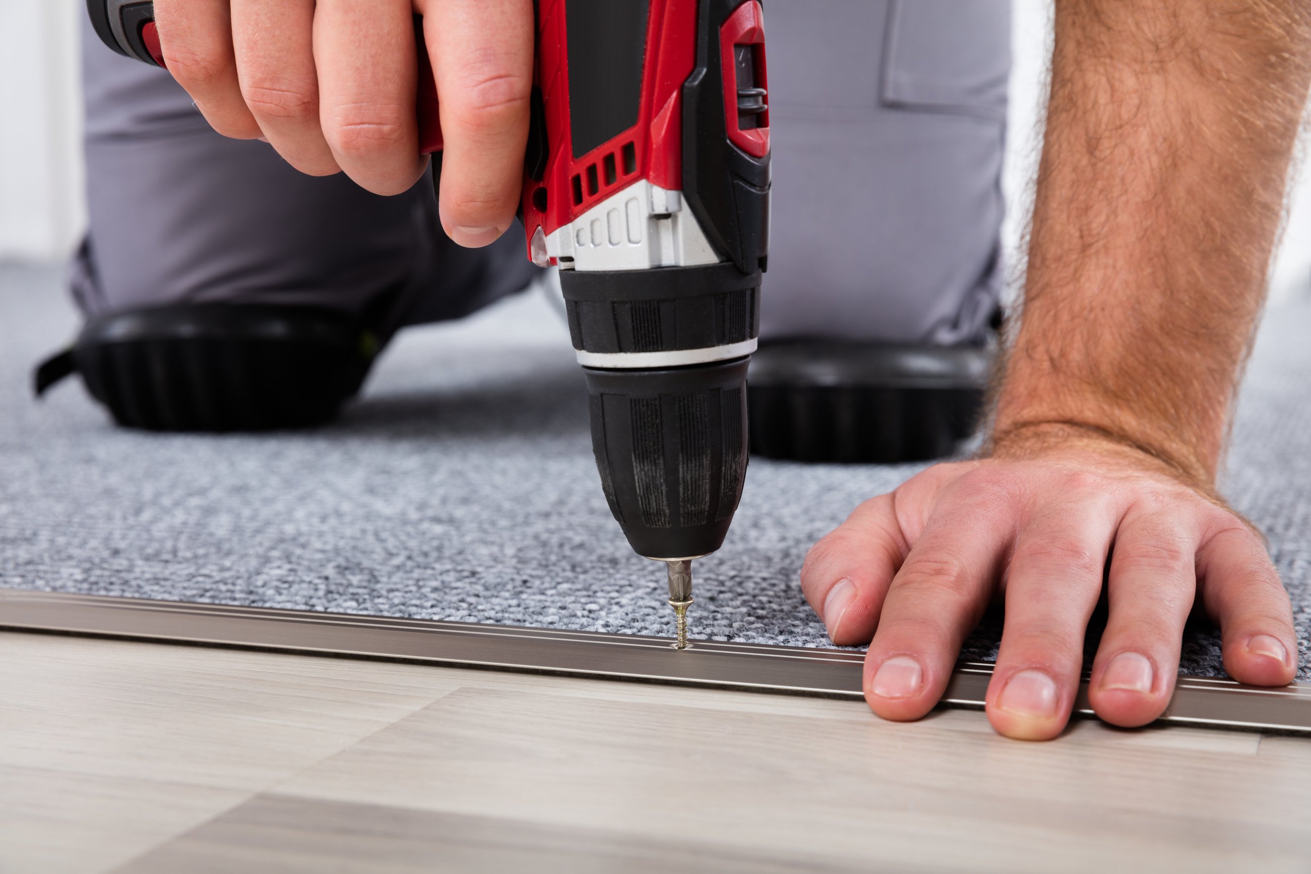 Person's Hand Installing Carpet On Floor